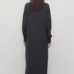 Back view of enzyme black loter dress on model wearing boots, against a white background.