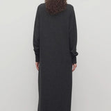 Back view of enzyme black loter dress on model wearing boots, against a white background.