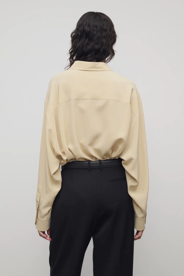 Back view of butter luka shirt on model wearing black pants, against a white background.