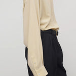 Side view of butter luka shirt on model wearing black pants, against a white background.