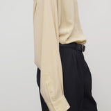 Side view of butter luka shirt on model wearing black pants, against a white background.