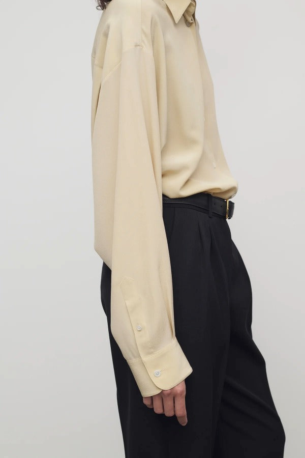 Side view of butter luka shirt on model wearing black pants, against a white background.