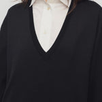 Front closeup view of black luza dress on model wearing white collar shirt, against a white background.