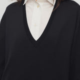 Front closeup view of black luza dress on model wearing white collar shirt, against a white background.