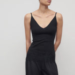 Front view of black makka top on model wearing black pants, against a white background.