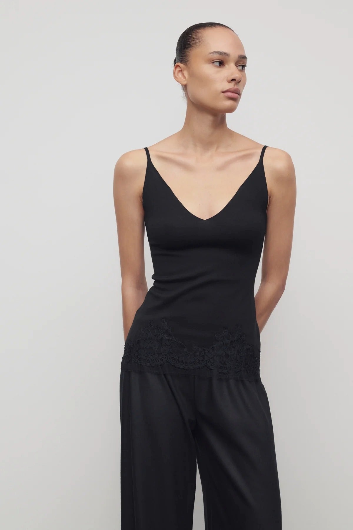 Front view of black makka top on model wearing black pants, against a white background.