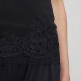 Front closeup of black makka top on model wearing black pants, against a white background.