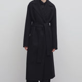 Front view of black malika coat on model wearing black pants and boots, against a white background.