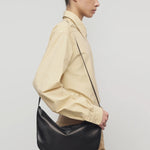 Side view of sand margan shirt on model wearing orange corduroys and brown shoulder bag, against a white background.