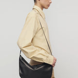 Side view of sand margan shirt on model wearing orange corduroys and brown shoulder bag, against a white background.