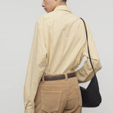 Back view of sand margan shirt on model wearing orange corduroys, brown belt and brown shoulder bag , against a white background.