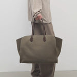Front view of taupe marlo 17 bag on model wearing khaki pants and beige shirt, against a white background.