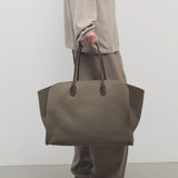 Front view of taupe marlo 17 bag on model wearing khaki pants and beige shirt, against a white background.
