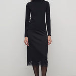 Front view of black mea skirt on model wearing black top and heels, against a white background.