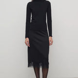 Front view of black mea skirt on model wearing black top and heels, against a white background.