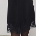Front closeup of black mea skirt on model wearing black tights against a white background.