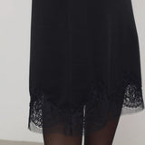 Front closeup of black mea skirt on model wearing black tights against a white background.