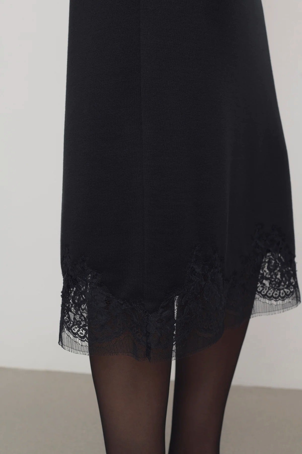 Front closeup of black mea skirt on model wearing black tights against a white background.