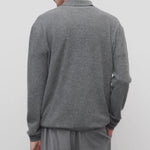 Back view of grey melange almot sweater on model wearing grey pants, against a white background.