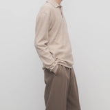 Side view of beige melange almot sweater on model wearing khaki pants against a white background.