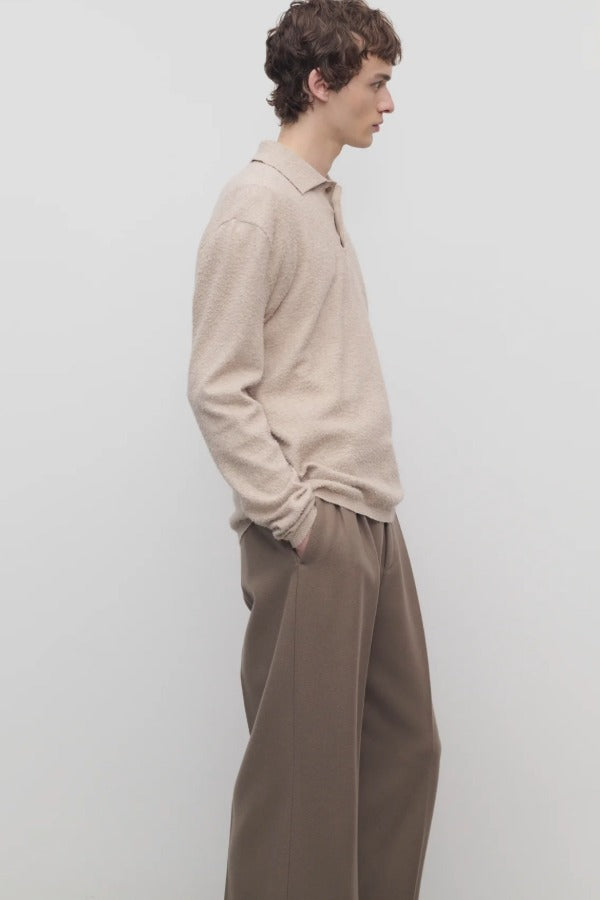 Side view of beige melange almot sweater on model wearing khaki pants against a white background.