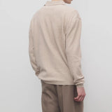 Back view of beige melange allmot sweater on model wearing khaki pants, against a white background.