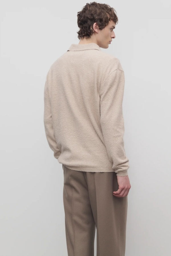 Back view of beige melange allmot sweater on model wearing khaki pants, against a white background.
