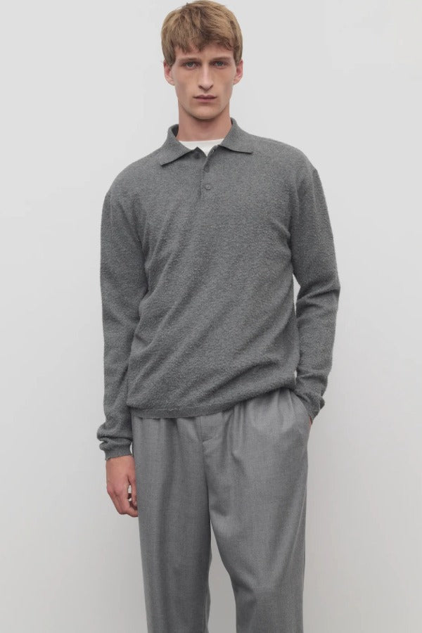Front view of grey melange almot sweater on model wearing grey pants, against a white background.