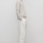 Side view of white belamy pant on model wearing beige top and sneakers, against a white background.