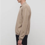 Side view of taupe men's franz sweater on model wearing black trousers, against a white background 