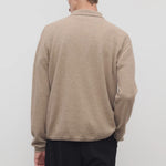 Back view of taupe men's franz sweater on model wearing black trousers, against a white background.
