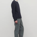 Side view of grey men's fred pants on model wearing black sweater and boots, against a white background.
