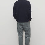 Back view of grey men's fred pants on model wearing black sweater and boots, against a white background.