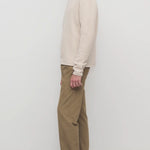 Side view of beige fred pant on model wearing oatmeal top and slides, against a white background.