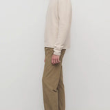 Side view of beige fred pant on model wearing oatmeal top and slides, against a white background.