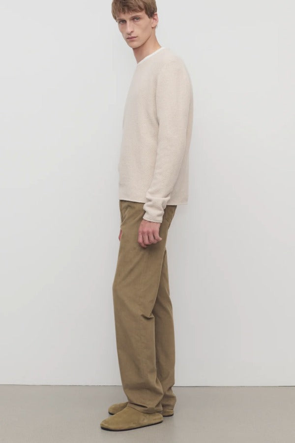 Side view of beige fred pant on model wearing oatmeal top and slides, against a white background.