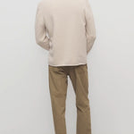 Back view of beige fred pant on model wearing oatmeal top and slides, against a white background.
