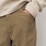 Front closeup view of beige fred pant on model wearing oatmeal top, against a white background.