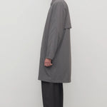 Side view of grey cobalt men's hesper coat on model wearing black pants and boots, against a white background.