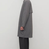 Side view of grey cobalt men's hesper coat on model wearing black pants and boots, against a white background.