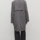 Back view of grey cobalt men's hesper coat on model wearing black pants and boots, against a white background.