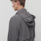 Side slanted closeup view of grey cobalt men's hesper coat on model, against a white background.
