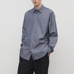 Front view of blue/white men's miller stripe shirt on model wearing black trousers, against a white background.