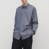 Front view of blue/white men's miller stripe shirt on model wearing black trousers, against a white background.