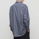 Back view of blue/white men's miller stripe shirt on model wearing black trousers, against a white background.