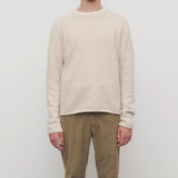 Front view of ecru nikola sweater on model wearing khakis, against a white background.