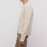 Side view of ecru nikola sweater on model wearing khakis against a white background.