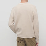 Back view of ecru nikola sweater on model wearing khakis, against a white background.