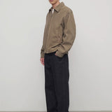 Side view of indigo rossen jean on model wearing khaki jacket and boots, against a white background.