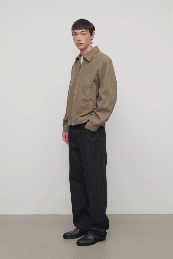 Side view of indigo rossen jean on model wearing khaki jacket and boots, against a white background.